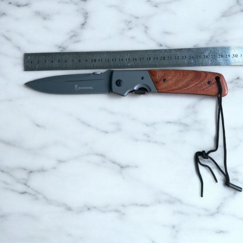 Дървена дръжка и въженце за захващане на нож Browning Нож Browning върху мраморен фон с метална линийка за размер