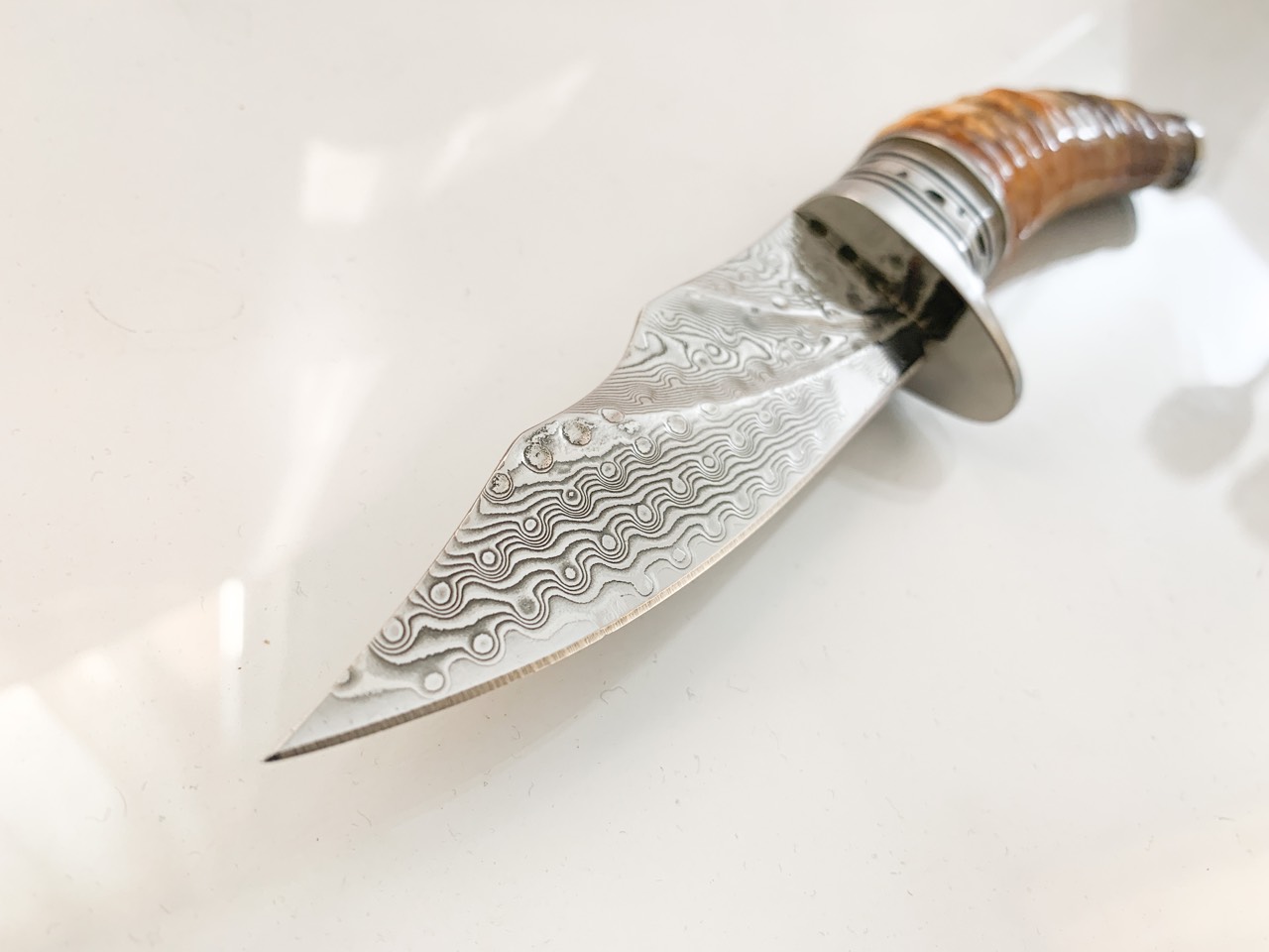 Ловен нож ръчно направен от дамаска японска стомана,дръжка от кориан имитиращ еленов рог и метален гард