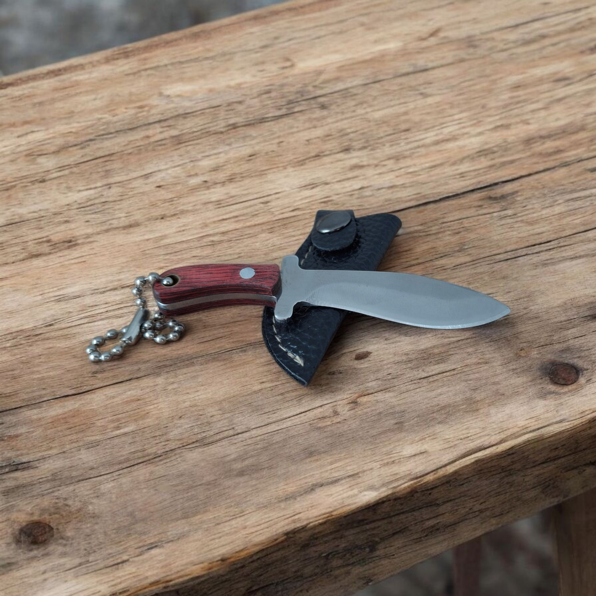 Джобен ловен нож с верижка и кожен калъф върху бял плат