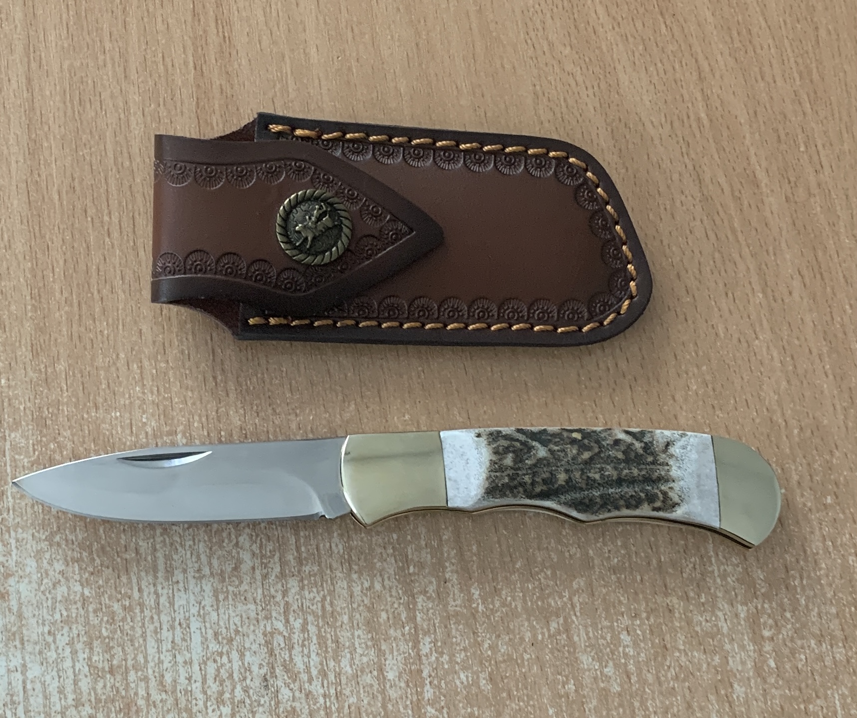 Ловен нож Elk Horn 195 с кожена кания върху дърво сред гора
